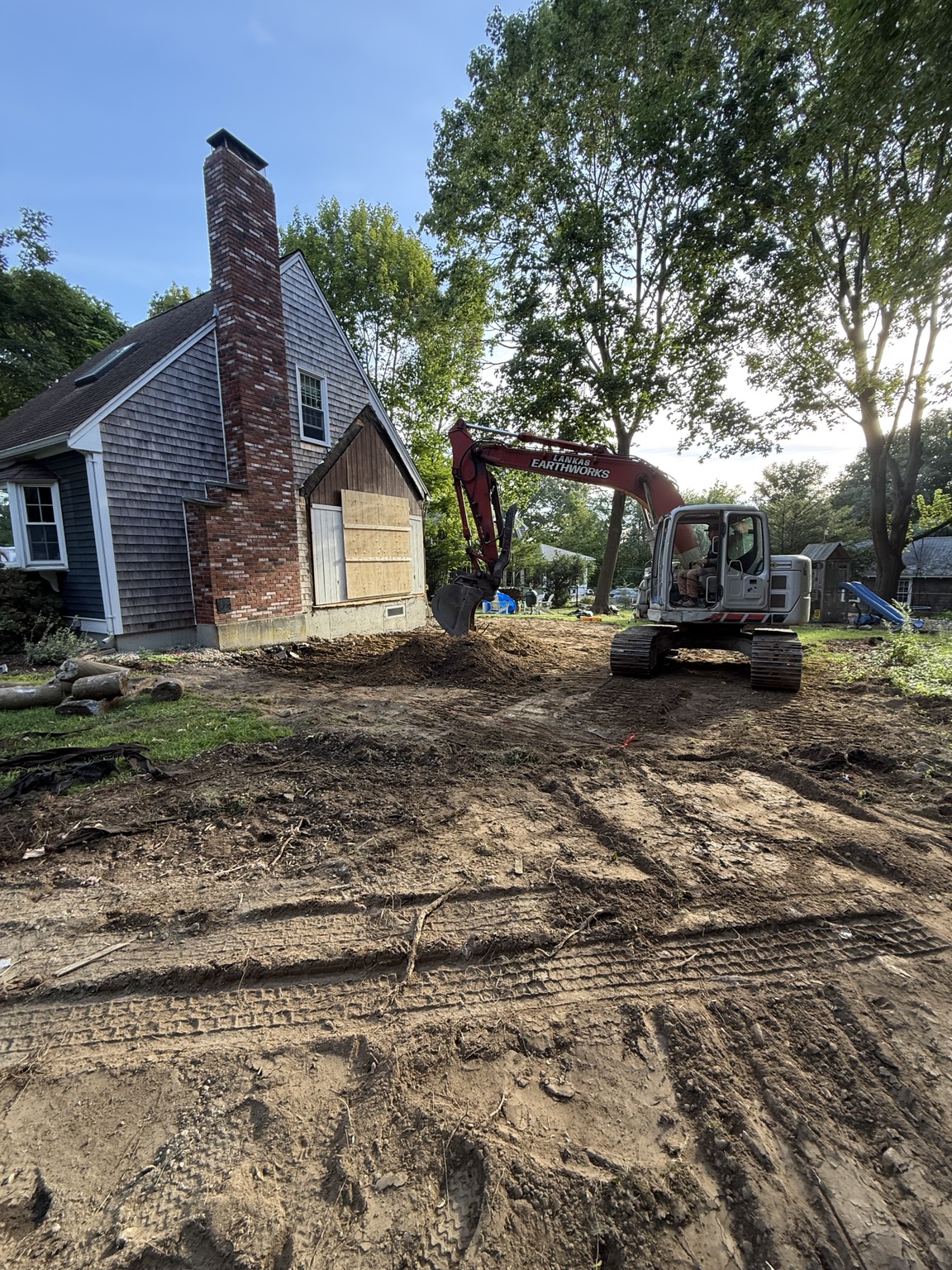 Excavator preparing the site beside a home after an addition was removed