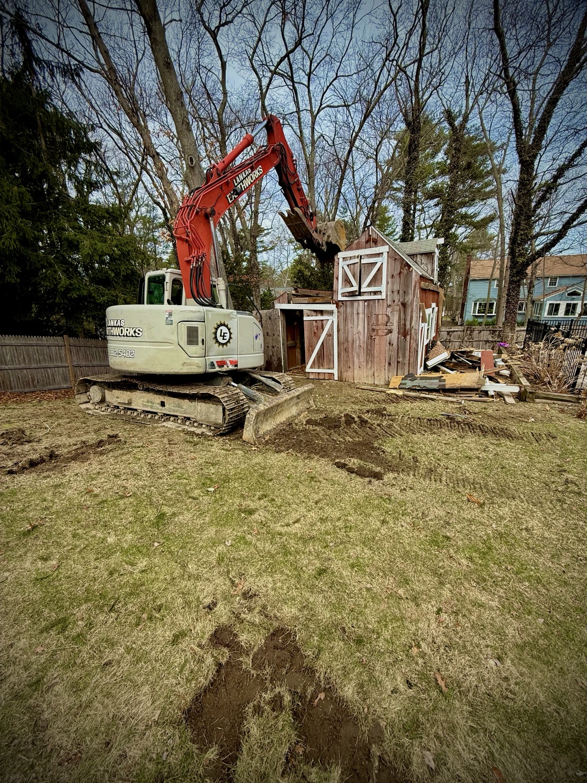 Excavator removing a residential outbuilding
