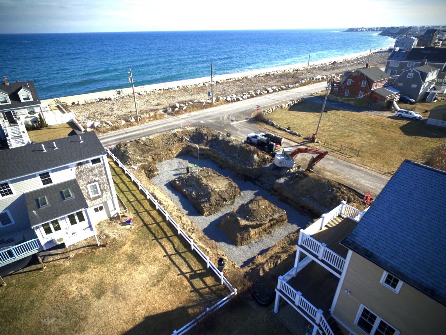 Aerial view of a coastal foundation excavation prepared with compacted stone